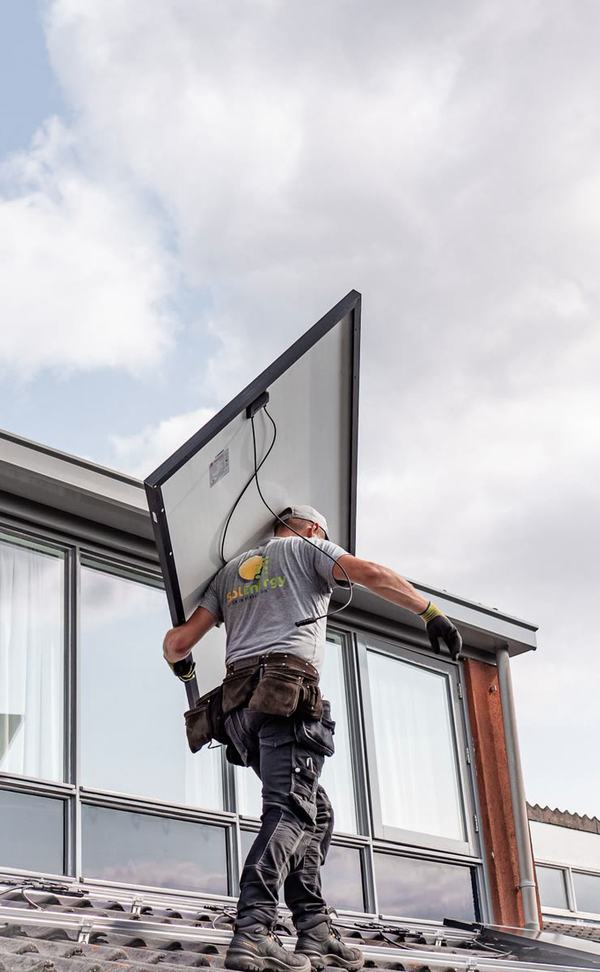 Instalador subiendo un panel solar a un tejado